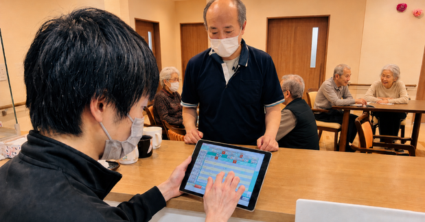 カウンターでタブレットの業務画面を操作し、職員と共有する様子